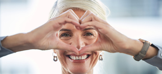 Image showing Portrait, hands and heart with a business woman in the office, feeling love for her corporate career. Face, emoji or hand sign with a senior female manager or ceo work looking happy and confident