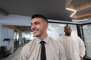 Image showing A group of young business professionals stands together, taking a well-deserved break from their busy workday, showcasing camaraderie, teamwork, and a moment of relaxation in their dynamic workplace