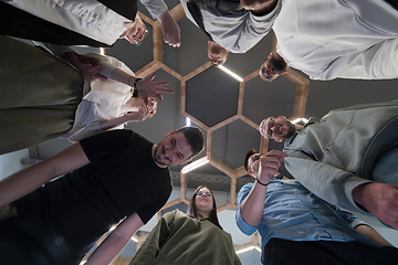 Image showing In a modern office, a group of young business professionals is captured in a warm and embracing hug, reflecting the spirit of unity, collaboration, and shared success in their dynamic workplace.