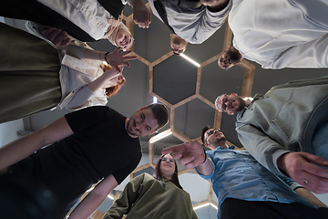 Image showing In a modern office, a group of young business professionals is captured in a warm and embracing hug, reflecting the spirit of unity, collaboration, and shared success in their dynamic workplace.