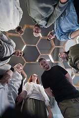 Image showing In a modern office, a group of young business professionals is captured in a warm and embracing hug, reflecting the spirit of unity, collaboration, and shared success in their dynamic workplace.