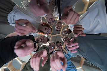 Image showing In a modern office, a group of young business professionals is captured in a warm and embracing hug, reflecting the spirit of unity, collaboration, and shared success in their dynamic workplace.