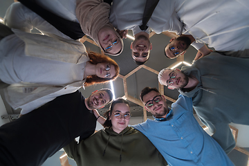 Image showing In a modern office, a group of young business professionals is captured in a warm and embracing hug, reflecting the spirit of unity, collaboration, and shared success in their dynamic workplace.