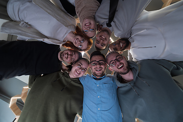 Image showing In a modern office, a group of young business professionals is captured in a warm and embracing hug, reflecting the spirit of unity, collaboration, and shared success in their dynamic workplace.