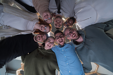 Image showing In a modern office, a group of young business professionals is captured in a warm and embracing hug, reflecting the spirit of unity, collaboration, and shared success in their dynamic workplace.