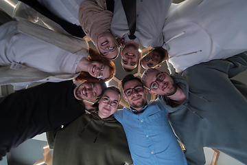 Image showing In a modern office, a group of young business professionals is captured in a warm and embracing hug, reflecting the spirit of unity, collaboration, and shared success in their dynamic workplace.