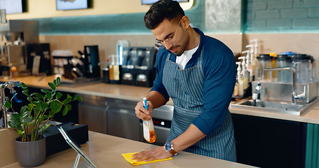 Image showing Waiter, man and cleaning table in cafe for dust, bacteria and dirt with cloth, spray or detergent. Barista, person or wipe wooden furniture in coffee shop or restaurant with chemical liquid for shine