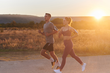 Image showing A handsome young couple running together during the early morning hours, with the mesmerizing sunrise casting a warm glow, symbolizing their shared love and vitality