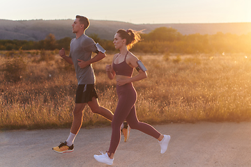 Image showing A handsome young couple running together during the early morning hours, with the mesmerizing sunrise casting a warm glow, symbolizing their shared love and vitality