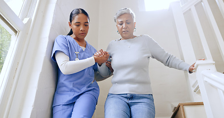 Image showing Woman, nurse and helping senior on stairs in retirement home for support, trust or healthcare. Female person, medical caregiver holding hands with retired or mature patient down a staircase at house