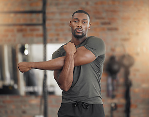 Image showing Black man, bodybuilder and stretching in gym for fitness, health or exercise with muscle, arms or focus. Man, strong or warm up for workout, training or performance for healthy body, wellness or life