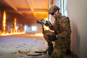 Image showing Soldier in action near window changing magazine and take cover