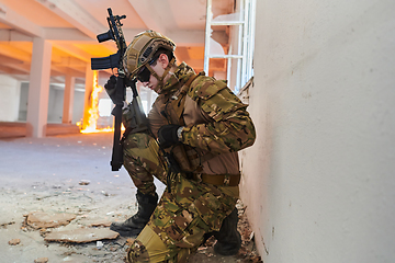 Image showing Soldier in action near window changing magazine and take cover