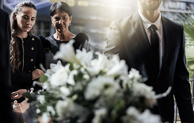 Image showing Funeral, coffin and family or friends at death, mourning and church burial event sad together. Depression, grief and christian religion gathering of people and women with support with flowers