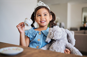 Image showing Children, imagination and tea party with a girl playing pretend at a table in her home alone. Kids, happy and game with a young female child drinking from a cup with a teddy bear in her house
