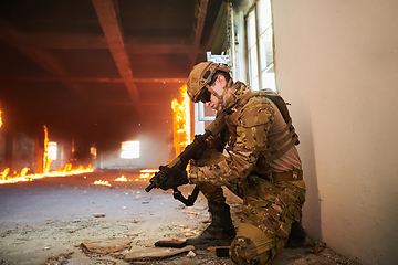 Image showing Soldier in action near window changing magazine and take cover
