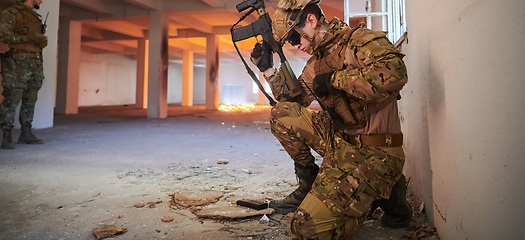 Image showing Soldier in action near window changing magazine and take cover