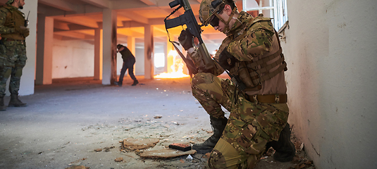 Image showing Soldier in action near window changing magazine and take cover