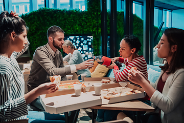 Image showing Eating pizza with diverse colleagues in the office, happy multi-ethnic employees having fun together during lunch, enjoying good conversation, and emotions