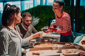 Image showing Eating pizza with diverse colleagues in the office, happy multi-ethnic employees having fun together during lunch, enjoying good conversation, and emotions