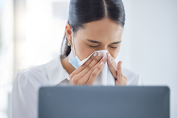 Image showing Covid, sick and blowing nose with a business woman sneezing into a tissue while suffering with a cold, flu or allergies in the office. Hands, nasal and hayfever with a young female employee at work