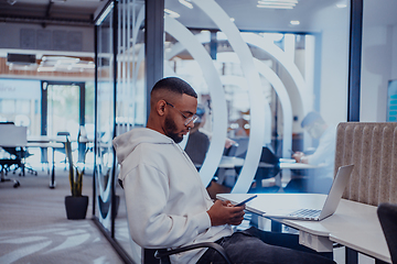 Image showing In a modern office setting, an African American businessman is diligently working on his laptop, embodying determination, ambition, and productivity in his professional environmen