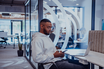 Image showing In a modern office setting, an African American businessman is diligently working on his laptop, embodying determination, ambition, and productivity in his professional environmen