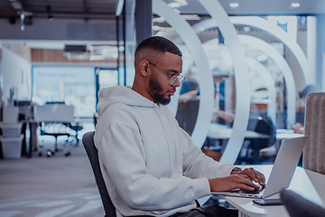 Image showing In a modern office setting, an African American businessman is diligently working on his laptop, embodying determination, ambition, and productivity in his professional environmen