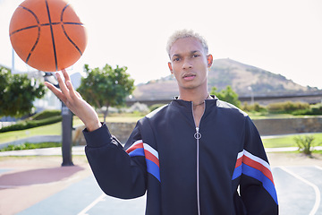 Image showing Fashion, court and man spinning a basketball on the sports ground before a training, exercise or cardio workout outdoors. Portrait, balance and young player in a cool urban jacket with ball on finger