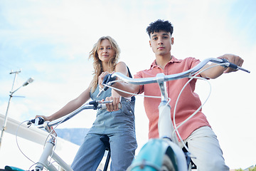 Image showing Bike, couple and carbon footprint with a man and woman riding a bicycle outdoor on a blue sky background from below. Portrait, travel and commute with a young male and female cycling on vacation