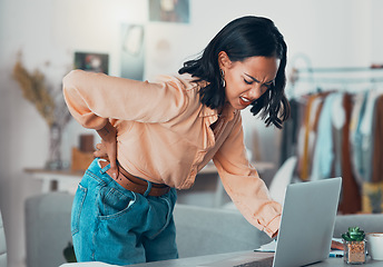 Image showing Back pain, discomfort and tired designer working on a laptop in a clothing boutique or store. Young overworked business owner, shop assistant suffering from injury, backache and pain at desk