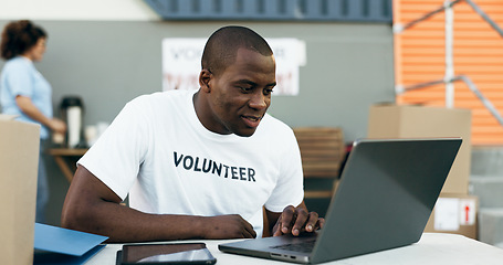 Image showing Volunteer man, laptop and reading for donation, clothes drive and smile for community service, scroll and web. African person, pc and social responsibility with boxes, charity and ideas for helping