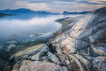 Image showing Rocky Shoreline with Water and Majestic Mountain Range