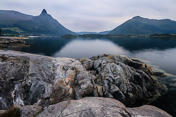 Image showing Rocky Shoreline with Water and Mountain Backdrop