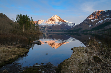 Image showing A Serene Lake Surrounded by Snow-Covered Mountains and Trees