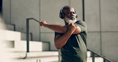 Image showing Fitness, headphones and senior black man stretching in city, workout and exercise for body health. Music, serious athlete and warm up on steps or stairs in urban town, listening to audio and thinking