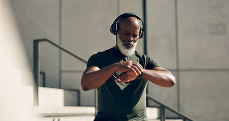 Image showing Fitness, headphones and black man on smart watch in city, workout progress and exercise results for body health. Music, senior athlete and check time on clock, heart rate and serious in town on steps