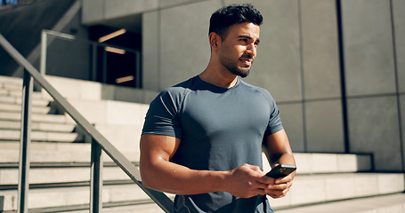 Image showing Fitness, phone and man in city on stairs after exercise, workout and training break. Smartphone, athlete and Indian person on steps outdoor, typing on mobile app, social media and thinking to relax