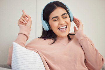 Image showing Singing woman wearing headphones to listen to music, enjoying favorite songs and having fun alone at home. Happy, cheerful and joyful female relaxing with good music and listening to a podcast