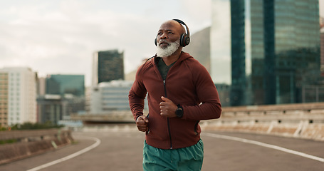 Image showing Running, city and senior man with headphones in training, streaming music and fitness. Retirement, black person or wellness of african runner for race in progress, urban road or marathon competition