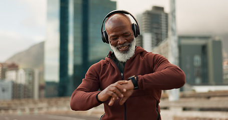 Image showing Man, headphones and smart watch in city for fitness, exercise results and workout performance. Happy senior african runner check timer, clock and healthy training progress with music in urban street