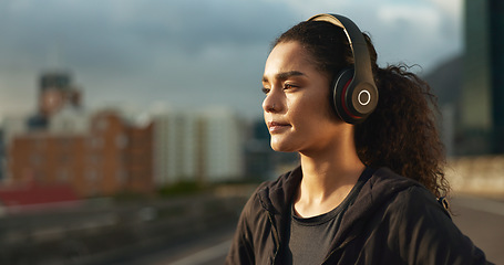 Image showing Woman, runner and headphones in city for fitness in evening sunset, music playlist workout sports. Female person, listen track and training thinking on street for cardio audio, exercise or streaming