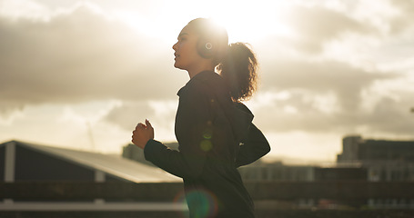 Image showing Woman, morning and running in city with headphones for fitness, workout and marathon training music. Sun lens flare, athlete or exercise podcast in Brazil for cardio wellness, health or sports radio