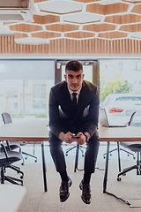 Image showing A businessman sitting on his desk, taking a moment to rest and unwind from a demanding workday, displaying a sense of tranquility and relaxation amidst the corporate environment