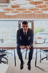 Image showing A businessman sitting on his desk, taking a moment to rest and unwind from a demanding workday, displaying a sense of tranquility and relaxation amidst the corporate environment