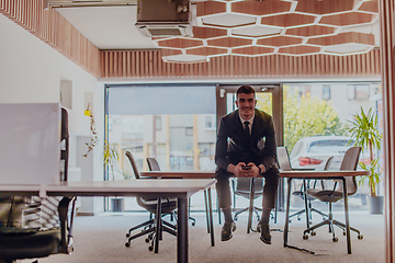 Image showing A businessman sitting on his desk, taking a moment to rest and unwind from a demanding workday, displaying a sense of tranquility and relaxation amidst the corporate environment