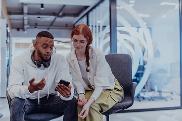 Image showing In a modern office African American young businessman and his businesswoman colleague, with her striking orange hair, engage in collaborative problem-solving sessions