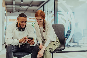 Image showing In a modern office African American young businessman and his businesswoman colleague, with her striking orange hair, engage in collaborative problem-solving sessions