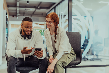 Image showing In a modern office African American young businessman and his businesswoman colleague, with her striking orange hair, engage in collaborative problem-solving sessions