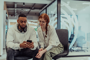 Image showing In a modern office African American young businessman and his businesswoman colleague, with her striking orange hair, engage in collaborative problem-solving sessions